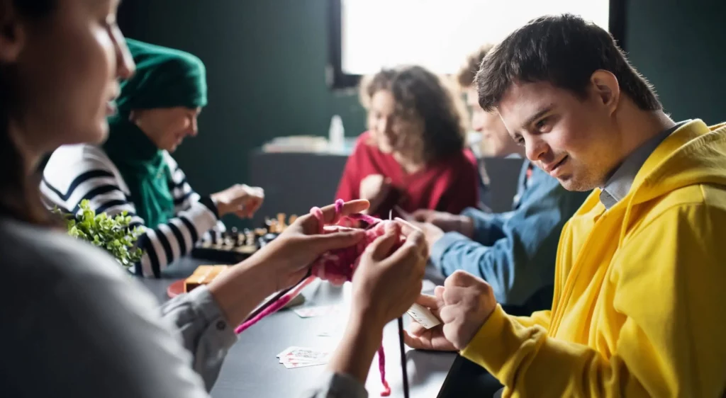 A group of people work on crafts with needles.